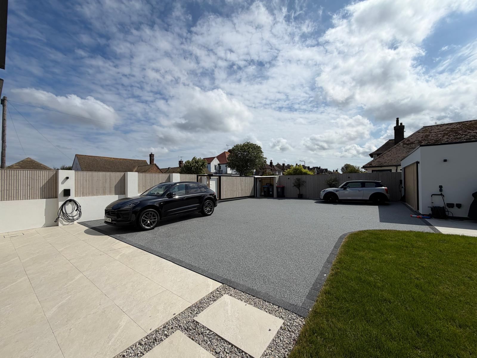 Driveway with two cars parked either side of a dual EV charger installation