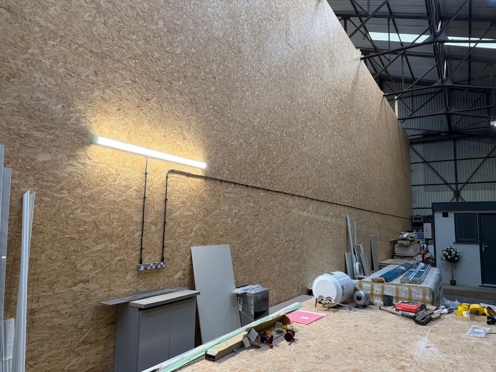 Close view of LED bench light and power outlet wiring in an industrial unit