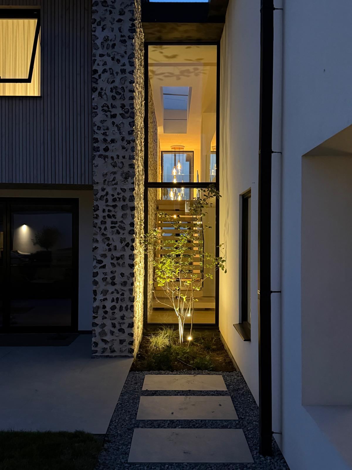 Glazed side passage lit at night showing the automated lighting scheme
