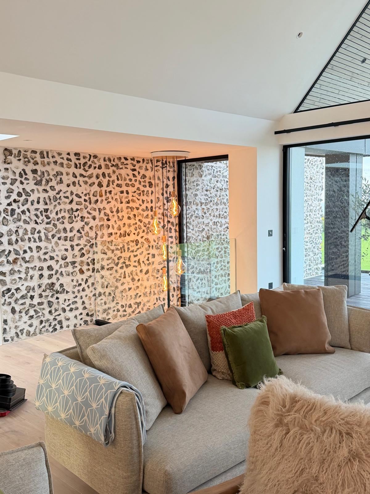 Open-plan living area with flint feature wall and suspended filament pendant lighting
